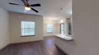 Located at 300 E Swisher Rd in Lake Dallas, Texas, this single-story residence offers a well-designed, open-concept floor plan that seamlessly connects the main living areas. The living room is bright and welcoming, featuring rich hardwood-style flooring, a ceiling fan with light fixture, and multiple windows dressed with horizontal blinds that allow ample natural light to filter in. It flows naturally into the dining area, which is illuminated by a stylish pendant light, reinforcing the cohesive open layout.

The kitchen is a standout feature, equipped with dark cabinetry, black appliances including a range, microwave, and refrigerator, and a granite-topped peninsula island with an integrated sink and pendant lighting above. The island provides additional counter space and serves as a practical divider between the kitchen and living areas.

The bedrooms are carpeted for comfort, each outfitted with a ceiling fan. The primary bedroom includes access to a walk-in closet with built-in shelving, offering generous storage. The bathroom features dark cabinetry with a wide vanity, a large mirror, and hardwood-style flooring that ties back to the main living areas.

Throughout, the neutral color palette of warm whites and greiges creates a clean, move-in-ready atmosphere suited for everyday living.