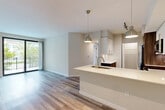 Located at 15572 SW 127th Ave in Miami, FL, this single-floor residence offers five bedrooms and two bathrooms within a thoughtfully designed open-concept layout. Light wood-tone flooring flows seamlessly throughout the living areas, complementing the neutral color palette and creating a clean, modern aesthetic.

The kitchen is a standout feature, showcasing two-tone cabinetry with white upper cabinets and wood-grain lower cabinets, stainless steel appliances including a refrigerator, range, and over-the-range microwave, a white quartz countertop, and a subway tile backsplash. A peninsula with an integrated sink and pendant lighting connects the kitchen to the open living area, which benefits from abundant natural light and sliding glass doors leading to a private balcony with greenery views.

The primary bedroom provides a comfortable retreat with dedicated closet space. Additional bedrooms are well-proportioned and feature wood-tone flooring and closets with built-in shelving. The two bathrooms differ in style: one offers a glass-enclosed walk-in shower, wood-grain vanity, and tile flooring, while the second includes a shower-tub combination, tile surround, and a natural light-admitting window. Two hallways and two closets further enhance the home's functional layout and storage capacity.