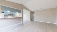This single-story, 3-bedroom, 3-bathroom home offers a thoughtfully designed layout with a clean, neutral aesthetic throughout. The open living area immediately impresses with its dramatic vaulted ceilings that amplify the sense of space, complemented by light wood-style flooring that runs seamlessly across the entire floor. Natural light filters in through multiple windows, creating a bright and welcoming atmosphere.

The kitchen features a galley-style design with distinctive blue cabinetry, granite-look countertops, a gas range, and ample upper and lower cabinet storage. A window above the sink provides a pleasant outdoor view of surrounding greenery. The kitchen connects to the living area via a convenient pass-through counter.

Each of the three bedrooms is well-proportioned, with ceiling fans, large windows with natural views, and light flooring. Each bedroom is paired with its own closet, offering practical storage solutions. The primary bedroom provides a comfortable, private retreat.

The three bathrooms maintain the home's cohesive style, featuring blue vanity cabinetry with granite countertops and large mirrors. Additional bathrooms include tub-shower combinations with clean, white fixtures. Neutral warm-gray wall tones are consistent throughout, tying the entire home together into a cohesive and functional living space.
