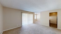 This single-floor, 2-bedroom, 2-bathroom home at 1968 Clinton Rd in Macon, Georgia offers a practical and comfortable layout with a warm, neutral color palette throughout. The spacious living room is carpeted and features a large sliding glass door dressed with vertical blinds, filling the space with natural light and offering a pleasant view of lush greenery outside. The layout flows naturally from the living area into a designated dining space, creating a cohesive open feel. The kitchen is efficiently designed with rich dark wood cabinetry, light countertops, hardwood-style flooring, and black appliances including a refrigerator and range. A pass-through counter connects it to the adjoining dining area. Both bedrooms are carpeted and well-lit, each featuring windows with horizontal blinds that allow ample natural light. The primary bedroom offers a comfortable, generously sized footprint. The two bathrooms are clean and functional, each equipped with a tub-shower combination and wood-style flooring. Three closets provide practical storage throughout the home. Textured ceilings are consistent across the unit, and neutral beige walls create a versatile backdrop suitable for a variety of interior styles.