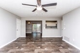 Located at 6300 Flat Rock Rd in Columbus, Georgia, this single-story home offers a thoughtfully arranged floor plan with consistent dark hardwood-style flooring throughout, creating a cohesive and polished look across every room.

The open living area flows naturally into the dining space, which features a classic pendant light fixture and a two-tone wall treatment with a chair rail accent. A sliding glass door in the dining area allows natural light to fill the space and provides direct access to the outdoors. The living room is generously sized, equipped with a ceiling fan and light fixture, and connects seamlessly to the rest of the home.

The kitchen is well-appointed with white shaker-style cabinetry, granite-patterned countertops, a matching backsplash, and black appliances including a range and over-the-range microwave. A pass-through opening connects the kitchen to the main living area, enhancing the open feel of the layout.

The bedrooms are comfortable in scale, each featuring ceiling fans and ample closet space. The primary bedroom includes dual closets. The bathroom offers a full tub-shower combination with a handheld showerhead, white cabinetry for storage, and a separate vanity area with a granite-topped sink, providing both function and a clean aesthetic throughout.