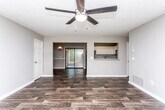 Located at 6300 Flat Rock Rd in Columbus, Georgia, this single-story home offers a thoughtfully arranged floor plan with consistent dark hardwood-style flooring throughout, creating a cohesive and polished look across every room.

The open living area flows naturally into the dining space, which features a classic pendant light fixture and a two-tone wall treatment with a chair rail accent. A sliding glass door in the dining area allows natural light to fill the space and provides direct access to the outdoors. The living room is generously sized, equipped with a ceiling fan and light fixture, and connects seamlessly to the rest of the home.

The kitchen is well-appointed with white shaker-style cabinetry, granite-patterned countertops, a matching backsplash, and black appliances including a range and over-the-range microwave. A pass-through opening connects the kitchen to the main living area, enhancing the open feel of the layout.

The bedrooms are comfortable in scale, each featuring ceiling fans and ample closet space. The primary bedroom includes dual closets. The bathroom offers a full tub-shower combination with a handheld showerhead, white cabinetry for storage, and a separate vanity area with a granite-topped sink, providing both function and a clean aesthetic throughout.