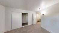 Located on Claremont Court in Santa Rosa, CA, this 2-bedroom, 1-bathroom upper-level unit offers a practical and efficiently designed layout accessed via a carpeted staircase. The floor plan connects two bedrooms and a shared bathroom through a central hallway, keeping the flow of the space straightforward and functional.

The primary bedroom is the largest of the two rooms, featuring soft wall-to-wall carpeting, clean white walls, and a sliding double-door closet with a full-width hanging rod for ample storage. The second bedroom mirrors the same neutral aesthetic, with plush carpeting, bright white walls, and a window overlooking neighboring rooftops and mature trees, allowing natural light to filter in.

The shared bathroom features a tub-shower combination lined with clean white tile, offering a simple and classic design. Throughout the unit, the consistent use of white paint, white trim and baseboards, and neutral carpet tones creates a cohesive, light, and airy atmosphere. Wall sconces in the hallway and primary bedroom provide warm ambient lighting. The staircase, framed by a black metal railing, connects this upper-level space to the floor below. Overall, the unit offers a clean, move-in-ready environment with a simple, no-frills design well-suited for practical everyday living.