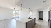 Located at 1100 West Temple Street in Los Angeles, this modern 2-bedroom, 2-bathroom unit offers a thoughtfully designed open-concept layout finished with clean, contemporary details throughout. Light wood-look flooring flows seamlessly across the entire space, complementing the crisp white walls and creating a bright, airy atmosphere.

The combined living and dining area is generously proportioned, featuring large windows that invite an abundance of natural light and offer views of the surrounding cityscape. A ceiling fan adds both style and function to the living space. The kitchen is a standout, outfitted with a large waterfall-edge island with an undermount sink and matte black faucet, two-tone gray and white cabinetry, white quartz countertops, subway tile backsplash, and a full suite of stainless steel appliances including a French door refrigerator, gas range, microwave, and dishwasher. Pendant lighting over the island adds a modern touch.

Each bedroom is well-sized and filled with natural light from large windows, with the second bedroom featuring a sliding barn-style closet door. Both bathrooms are finished in a modern palette, with one showcasing dramatic black hexagonal floor tile, a floating gray vanity, white quartz countertop, matte black fixtures, and a tub-shower combination with built-in shelving. The hallway connects the bedrooms and includes dedicated closet storage.