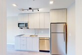 Located at 2310 Cochrane St in Detroit, MI, this efficiently designed studio offers a thoughtfully organized single-floor layout. The open-plan main area seamlessly integrates the living, dining, and kitchen zones, all finished with light hardwood-style flooring that enhances the sense of space and brightness throughout.

The kitchen is outfitted with contemporary light wood cabinetry extending to the ceiling for generous storage, a flat cooktop, stainless steel refrigerator, dishwasher, and built-in microwave. Track lighting above the kitchen adds focused illumination to the workspace. Recessed ceiling lights throughout the main area provide consistent, clean lighting.

The living area benefits from two windows that invite natural light and offer views of the surrounding neighborhood, complemented by a wall-mounted HVAC unit for year-round climate control. Neutral warm-gray walls provide a versatile backdrop throughout.

The bathroom features a full soaking tub and shower combination, a white vanity with under-sink storage, and tile flooring that coordinates with the overall palette. Additional conveniences include a dedicated laundry area and a closet for storage. The space presents a clean, modern aesthetic with a cohesive neutral color scheme suited to a variety of interior styles.