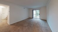 This single-floor residence offers a practical and comfortable layout designed for everyday living. The kitchen is thoughtfully equipped with warm medium-toned wood cabinetry, dark countertops, and a full suite of black appliances including a refrigerator, electric range, built-in microwave, and dishwasher. Tile flooring runs throughout the kitchen, providing a durable and easy-to-maintain surface. A breakfast bar-style counter separates the kitchen from the adjacent living area, which features plush carpeting, crown molding, and a sliding glass door that opens to a private balcony overlooking lush greenery — bringing in an abundance of natural light.

The bedrooms are generously proportioned, each finished with soft carpeting and ample closet space. The space includes two full bathrooms, both featuring warm wood vanity cabinetry, white countertops, and tile flooring. The primary bathroom offers an extended double-sink vanity with a large mirror, while the secondary bathroom includes a combined tub and shower unit. Both bathrooms are finished in a clean, neutral palette that contributes to the overall bright and inviting ambiance of the home.