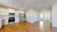 This single-story home in Tonganoxie, Kansas offers a thoughtfully arranged layout with two bedrooms and two bathrooms. The interior features a consistent neutral color palette and clean white trim throughout, creating a bright and cohesive aesthetic.

The kitchen is a standout space, outfitted with white shaker-style cabinetry, white subway tile backsplash, light countertops, and a full suite of stainless steel appliances including a refrigerator, range, microwave, and dishwasher. Warm wood-look flooring runs through the kitchen and living areas, adding visual continuity.

The living room benefits from natural light through a large front window and a glass-paneled entry door, complemented by a ceiling fan overhead. Both bedrooms are carpeted and include ceiling fans, with one bedroom featuring a double-door closet. The primary bathroom includes a walk-in tiled shower with a sliding glass door and white vanity cabinetry, while the second bathroom offers a tub-shower combination with matching wood-look flooring and a white vanity. Together, these spaces deliver a clean, modern living environment.