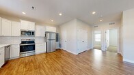 This single-story home in Tonganoxie, Kansas offers a thoughtfully arranged layout with two bedrooms and two bathrooms. The interior features a consistent neutral color palette and clean white trim throughout, creating a bright and cohesive aesthetic.

The kitchen is a standout space, outfitted with white shaker-style cabinetry, white subway tile backsplash, light countertops, and a full suite of stainless steel appliances including a refrigerator, range, microwave, and dishwasher. Warm wood-look flooring runs through the kitchen and living areas, adding visual continuity.

The living room benefits from natural light through a large front window and a glass-paneled entry door, complemented by a ceiling fan overhead. Both bedrooms are carpeted and include ceiling fans, with one bedroom featuring a double-door closet. The primary bathroom includes a walk-in tiled shower with a sliding glass door and white vanity cabinetry, while the second bathroom offers a tub-shower combination with matching wood-look flooring and a white vanity. Together, these spaces deliver a clean, modern living environment.