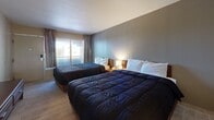 Located at 13031 Central Ave NE in Albuquerque, New Mexico, this efficiently designed one-bedroom, one-bathroom unit offers a well-organized layout across a single floor. The generously proportioned bedroom serves as the centerpiece of the space, comfortably accommodating two full-sized beds with warm wood headboards, neutral gray walls, and light wood-style flooring. A sliding window with drape panels allows natural light to fill the room, creating a bright and restful atmosphere.

The kitchen features warm-toned wood cabinetry with raised-panel doors, light granite-style countertops, a stainless steel sink, a smooth-top electric cooktop, and an over-the-range microwave. Light tile flooring and textured walls lend the kitchen a clean, practical aesthetic with ample cabinet storage both above and below the counters.

The bathroom is finished with beige ceramic tile on both the floor and the tub surround, a full soaking tub with shower, and a curtain rod with a classic white curtain. The space is clean and functional, with grab bar accessibility accommodated near the tub.

Overall, this unit delivers a straightforward and practical living environment, thoughtfully arranged to maximize every square foot for comfortable day-to-day use.