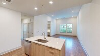 This well-appointed 2-bedroom, 3-bathroom residence at 80 Mill St in Hanover, MA offers a thoughtfully designed single-floor layout with modern finishes throughout. The open-concept kitchen and living area serves as the heart of the home, anchored by a large center island with a white quartz countertop and undermount sink. Light wood cabinetry, stainless steel appliances, and a tile backsplash complete the kitchen's contemporary aesthetic, all set atop warm hardwood flooring that extends into the living area. Recessed lighting and large windows flood the space with natural light and views of surrounding greenery.

The primary bedroom features soaring ceilings, plush carpeting, and a private en-suite bathroom, along with a spacious walk-in closet outfitted with wire shelving on multiple levels for ample storage. A second bedroom also benefits from tall ceilings and generous natural light through multiple windows. Each closet includes built-in wire shelving systems, maximizing organizational capacity.

The three bathrooms are finished with elegant marble-style tile flooring and surround, floating wood-tone vanities with quartz countertops, and brushed nickel fixtures. One bathroom features a full soaking tub with a marble-tiled surround. A hallway connects the rooms efficiently, rounding out a cohesive and modern living experience.