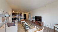 This single-floor residence presents a clean, contemporary design throughout. The expansive main living area is finished with smooth hardwood-style flooring and crisp white walls, drawing the eye toward a set of sliding glass doors that open onto a private balcony framed by lush tree views, bringing natural light deep into the space.

The kitchen is a standout feature, outfitted with rich dark-espresso cabinetry extending to the ceiling, white quartz countertops, a large undermount sink, and a full suite of stainless steel appliances including a refrigerator, range, microwave, and dishwasher. Pendant lighting and light wood-style flooring complete the polished look.

The bedrooms are carpeted for comfort, each offering natural light through large windows with leafy outdoor views. One bedroom features a spacious walk-in closet with built-in shelving. The two bathrooms are finished consistently with dark vanity cabinetry, white countertops, and wood-look flooring. One bathroom includes a soaking tub and shower combination, while the other features a glass-enclosed walk-in shower. The overall aesthetic is modern, neutral, and cohesive throughout.