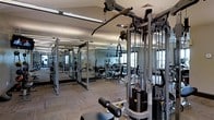 Located at 6400 Preserve Crossing Blvd N in Gahanna, Ohio, this single-floor fitness center offers a comprehensive workout environment designed to accommodate a wide range of exercise needs. The space is outfitted with an extensive array of strength training equipment, including multi-station cable machines, pull-down systems, weight stacks, and free-weight benches, providing users with versatile options for full-body conditioning. Cardio equipment, including elliptical machines, is positioned throughout the room to complement the strength training area. The facility is finished with durable, low-maintenance flooring suited for heavy equipment and high-traffic use. Full-length mirrors line the walls, visually expanding the space while allowing users to monitor their form during workouts. Overhead fluorescent lighting ensures the entire area is brightly and evenly illuminated, contributing to a focused and functional atmosphere. Windows along the perimeter allow natural light to filter in, enhancing the overall environment. The open layout promotes an efficient flow between equipment stations, making the space accessible and easy to navigate. This well-equipped fitness center serves as a practical and fully functional facility for residents and users seeking a convenient on-site exercise space.