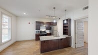 Located at 204 S Riverfront Dr in Jenks, Oklahoma, this 2-bedroom, 2-bathroom residence offers a thoughtfully designed single-floor layout. The open-concept kitchen serves as a centerpiece, featuring rich dark-wood cabinetry, granite countertops, a kitchen island with a sink, stainless steel appliances including a gas range and refrigerator, subway tile backsplash, and stylish pendant lighting. A built-in open shelving unit adds additional storage and display space. Warm wood-style flooring runs throughout the entire residence, creating a cohesive and inviting atmosphere. The living area benefits from large windows that bring in abundant natural light and provide views of the surrounding area. Each bedroom is bright and well-proportioned, with ceiling fans and windows fitted with blinds. The primary bedroom offers a comfortable amount of space. Both bathrooms are equipped with accessibility features, including grab bars and a bench in the tub/shower area, as well as wall-mounted sinks and well-lit vanity mirrors. The overall design balances modern finishes with practical functionality, making this a well-appointed and accessible residence in the Jenks community.