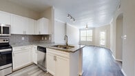 This 2-bedroom, 1-bathroom residence in Lewisville, TX offers a well-designed single-story layout with modern finishes throughout. The open-concept kitchen and living area forms the heart of the home, anchored by a peninsula with granite countertops and a double-basin sink. The kitchen is equipped with a full suite of stainless steel appliances — including a refrigerator, range, microwave, and dishwasher — complemented by crisp white shaker cabinetry and a classic subway tile backsplash. Track lighting illuminates the kitchen, while a ceiling fan adds comfort to the adjoining living area. Wood-style plank flooring flows seamlessly across the entire space, adding warmth and continuity. Crown molding accents the living area, which benefits from abundant natural light through large windows and direct access to a private balcony with outdoor views. The bedrooms are generously proportioned, with the primary bedroom featuring a ceiling fan, a large window overlooking greenery, and a spacious sliding-door closet with built-in shelving. The bathroom is finished with a granite-topped vanity, white cabinetry, and a full tub-shower combination. A hallway and dedicated closet round out this thoughtfully arranged and move-in-ready home.