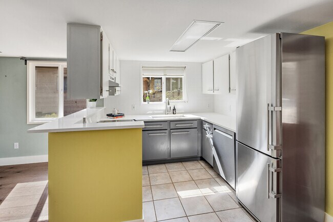 Kitchen updates include new tile walls from counter to ceiling and backsplash detail behind kitchen bar. Crisp white quartz counters with new drop-in sink and faucet, slide in range, brand new KitchenAid dishwasher & Liebherr refrigerator. - 7051 8th Ave NW