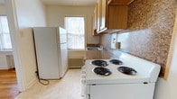 Located at 910 New Holland Ave in Lancaster, Pennsylvania, this single-floor space offers a practical and well-organized layout designed for comfortable everyday living. The kitchen is a standout feature, showcasing warm wood-toned upper cabinetry that provides generous storage, complemented by dark granite-style countertops and a matching tile backsplash that adds texture and visual interest. A full suite of white appliances is included, featuring a four-coil electric range, a full-size refrigerator, and a double-basin sink positioned beneath a window that invites natural light into the space. A classic cast-iron radiator beneath the window speaks to the building's character while providing reliable warmth. The light-toned flooring throughout contributes to a clean, open feel. The overall ambiance of the space is functional and inviting, with thoughtful details that balance practicality with comfort. Situated in Lancaster, PA, residents enjoy convenient access to the city's local amenities, dining, and community resources, making this a well-positioned space for those seeking a straightforward and comfortable place to call home.