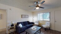 This single-floor residence offers a thoughtfully designed layout that balances comfort and functionality. The living room serves as the heart of the home, featuring wood-look flooring, a textured ceiling with a ceiling fan, and a large window with vertical blinds that invite natural light while providing privacy. The space comfortably accommodates a full sofa and accent seating, creating an inviting atmosphere.

Adjacent to the living area, the dining space provides a dedicated setting for meals, centered around a dark wood dining table with matching chairs and accented by a decorative geometric mirror on the wall.

The kitchen is efficiently designed with white cabinetry, light countertops, and black appliances including a refrigerator, dishwasher, and range. A skylight feature brightens the workspace, while wood-look flooring ties the area together seamlessly.

The bedrooms are carpeted for comfort, each equipped with a ceiling fan and windows with vertical blinds that bring in natural light. Both rooms offer a calm, restful ambiance.

The two full bathrooms are finished with white vanities, large mirrors, and wood-look flooring. Each bathroom features a shower-tub combination with a curtain, providing practical and clean spaces throughout the residence.