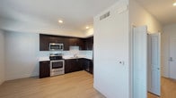 This single-floor residence offers a clean, contemporary design throughout its well-organized layout. The kitchen is a standout feature, showcasing rich dark espresso cabinetry that extends from floor to ceiling, paired with crisp white countertops and light wood-style flooring that creates a striking contrast. A full suite of stainless steel appliances — including a refrigerator, electric range, built-in microwave, and dishwasher — provides everything needed for everyday cooking. The kitchen opens toward the living area, creating a connected and functional flow throughout the space. The bedroom is finished with wall-to-wall carpet for added comfort and features a horizontal window that invites natural light into the room while maintaining privacy. The bathroom is finished with the same light wood-style flooring as the kitchen and includes a full soaking tub with a shower, a toilet, and clean white walls that create a bright, airy feel. Throughout the unit, white walls, recessed lighting, and consistent flooring choices tie the space together with a cohesive modern aesthetic. The overall ambiance is fresh, minimal, and move-in ready.