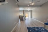 This two-story home showcases a contemporary design with a neutral gray and white color palette, light hardwood flooring, and clean architectural lines carried consistently throughout both levels. The main floor opens into a spacious living area illuminated by natural light from large windows and a sliding glass door that connects to the outdoor space, enhancing the sense of openness. A ceiling fan anchors the living space, which flows seamlessly into the kitchen and dining area.

The kitchen is a standout feature, equipped with rich dark-toned cabinetry, granite countertops, stainless steel appliances including a gas range, microwave, refrigerator, and dishwasher. A large center island provides additional prep space and casual seating. A dedicated laundry area includes a full-size washer and dryer beneath generous upper cabinetry for storage.

A full bathroom on the main level features granite countertops, a single vanity, and a tub-shower combination with sliding frosted glass doors. The upper floor continues the hardwood flooring and hosts well-sized bedrooms, including a primary suite with an en-suite bathroom and ceiling fan. Additional bathrooms mirror the granite vanity and tub-shower design found throughout the home, maintaining a cohesive and polished aesthetic.