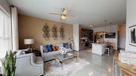 This single-story residence at The Henry presents a thoughtfully designed open-concept layout that seamlessly connects the main living areas. The living room is a welcoming space anchored by polished concrete flooring, a ceiling fan, and large windows dressed with drapes and blinds that invite generous natural light and outdoor views. A warm accent wall adds depth and character to the room.

The kitchen is a functional and stylish centerpiece, featuring dark espresso-toned cabinetry extending to the ceiling, granite countertops, and a full suite of stainless steel appliances including a range, microwave, and refrigerator. A peninsula with pendant lighting overhead provides additional prep space and casual seating, making it ideal for both cooking and entertaining.

The bedroom offers a serene retreat with a teal accent wall, large windows that bring in natural light, and ample room for generous furnishings. The polished concrete flooring continues throughout, lending a cohesive contemporary feel to the space.

The bathroom is accessed via a private hallway and features a vanity with a white countertop, cabinetry for storage, and well-placed lighting. Throughout the residence, the clean lines, neutral palette, and modern finishes create a polished and cohesive living environment.