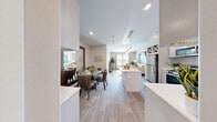 Located in Henderson, NV, this well-appointed one-bedroom, one-bathroom residence offers a thoughtfully designed single-level layout. The open-concept main area seamlessly combines the kitchen, dining room, and living room, creating a bright and cohesive gathering space. Light wood-style flooring flows throughout, complementing the neutral color palette and abundant natural light streaming in through large windows.

The kitchen is a standout feature, showcasing crisp white shaker cabinetry, quartz countertops, a subway tile backsplash, a central island with pendant lighting, and a full suite of stainless steel appliances including a gas range, microwave, refrigerator, and dishwasher. The dining area comfortably accommodates a full table, while the living room benefits from oversized windows that invite plenty of natural light.

The primary bedroom is generously proportioned, boasting dramatic vaulted ceilings, a ceiling fan, large windows, plush carpeting, and a sliding-door closet. The full bathroom features a single-sink vanity with a backlit mirror, wood-look tile flooring, and a shower-tub combo. A dedicated in-unit laundry room houses a full-size top-load washer and dryer with built-in shelving, rounding out this functional and stylish residence.