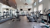 Located at Francis Way in Hawthorne, Bloomfield, Connecticut, this well-equipped fitness center offers a comprehensive workout environment designed to support a wide range of exercise routines. The space is characterized by soaring vaulted ceilings that lend an open, airy atmosphere, complemented by large windows positioned at multiple heights to flood the interior with natural light and provide views of the surrounding community.

The cardio zone features a row of Precor treadmills and elliptical machines, all positioned to take advantage of the natural light streaming through the windows. A dedicated strength training area includes a cable machine system, adjustable benches, and weight racks, while full-length mirrors along the walls enhance both the sense of space and functional use during workouts.

For functional and flexibility training, the fitness center provides a collection of stability balls, medicine balls, and a tiered dumbbell rack. The rubber-floored space also includes mounted flat-screen televisions for entertainment during cardio sessions, and an overhead ceiling fan ensures comfortable air circulation throughout.

The overall ambiance is modern and motivating, with a dramatic motivational mural displayed prominently on the upper wall, reinforcing an energetic and goal-oriented atmosphere throughout the facility.
