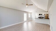 Located at 5049 Red Cherry Ct in Columbus, Ohio, this 2-bedroom, 2-bathroom single-floor home offers a well-designed layout that maximizes functionality and comfort. The living room immediately impresses with soaring vaulted ceilings, light wood-look flooring, a ceiling fan, and a striking arched window that floods the space with natural light, creating an open and airy atmosphere. The kitchen and living area flow seamlessly together, anchored by a large granite-topped island with a built-in sink and pendant lighting. White shaker cabinetry, dark granite countertops, and a full suite of stainless steel appliances — including a range, microwave, and refrigerator — complete this polished culinary space. The primary bedroom is generously sized, carpeted for warmth, and provides direct access to an en-suite bathroom. The second bedroom is equally comfortable, also featuring plush carpet, a ceiling fan, and access to natural light. Both bathrooms are clean and functional, featuring white vanities with brushed nickel fixtures and tub/shower combinations. A dedicated laundry room houses full-size washer and dryer units beneath overhead cabinetry for added storage. Soft gray walls and white trim throughout lend a cohesive, modern feel to the entire home.