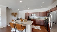 Located at 1105 Longhorn Rd in Fort Worth, TX, this single-story residence offers two bedrooms and two bathrooms within a thoughtfully designed floor plan. The open-concept kitchen and living area serves as the heart of the home, featuring rich espresso-toned cabinetry, granite countertops, a subway tile backsplash, and stainless steel appliances including a range, microwave, and refrigerator. A peninsula with bar seating provides additional dining and entertaining space, while wood-style flooring and recessed lighting enhance the warm, modern aesthetic. Crown molding and a ceiling fan add refined detail to the living room, which is brightened by large windows and a glass-panel door that invites natural light. The primary bedroom offers a generous layout with a built-in closet, while the second bedroom features plush carpeting, a large window with outdoor views, and a ceiling fan. Both bathrooms are finished with granite vanity counters, dark wood cabinetry, and tiled tub-shower combinations. A hallway and dedicated closet provide practical storage solutions throughout. The overall ambiance is warm and cohesive, blending contemporary finishes with comfortable, functional living spaces.