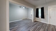 Located at 308 Grove St N in the heart of Saint Petersburg, FL, this efficiently designed single-floor unit offers a practical layout comprising a living room, kitchen, bathroom, and entrance. Throughout the space, wood-look plank flooring provides a cohesive and clean aesthetic, complemented by soft gray and white wall tones that contribute to a bright, neutral ambiance.

The living area is open and airy, featuring a ceiling fan with light fixture and multiple windows dressed with dark curtains, allowing for both natural light and privacy. The space connects seamlessly to the adjacent entrance area, creating a smooth flow through the unit.

The kitchen is appointed with white raised-panel cabinetry, dark granite-style countertops, and a full-size refrigerator. A window above the counter brings in natural light, enhancing the functionality of the space. The layout is efficient, making practical use of every corner.

The bathroom is clean and straightforward, featuring a white vanity with a dark-finish faucet, a bathtub, and a window that provides natural ventilation and light. The light wood-look flooring carries through from the main living areas, maintaining visual consistency.

The entrance serves as a transitional space connecting the interior rooms, reinforcing the unit's logical and accessible flow throughout.