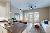 Located in Maryland Heights, Missouri, this well-appointed one-bedroom, one-bathroom residence offers a thoughtfully designed single-floor layout that maximizes functionality and style. The open-concept kitchen and living area serves as the heart of the home, where a striking curved island with dark stone countertops and seating anchors the space. The kitchen is outfitted with white shaker cabinetry, a classic subway tile backsplash, stainless steel appliances, and stylish pendant lighting that adds a warm, modern ambiance. Light wood-style flooring flows throughout, complementing the neutral warm-gray walls. The living area benefits from abundant natural light streaming through large windows and a glass door that opens to a private outdoor balcony, while a ceiling fan keeps the space comfortable. The bedroom offers a serene retreat with plush carpeting, generous closet access, and a calm, neutral palette. The bathroom features a full tub-shower combination with clean white subway tile surround and brushed nickel fixtures. Additional conveniences include an in-unit laundry area with a full-size washer, a utility room, and two closets for ample storage throughout.