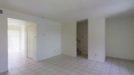 This two-story residence offers a straightforward and functional layout designed to maximize usable space across both levels. The main floor features light-toned ceramic tile flooring that runs throughout, lending a clean and cohesive look to the interior. Walls are finished in a neutral white palette, creating a bright and open atmosphere that reflects natural light effectively. A textured ceiling adds subtle character to the space. The main living area is open and generously proportioned, providing flexibility for various furniture arrangements. A closet is accessible on the main level, offering convenient storage. An interior staircase with a wooden handrail connects the two floors, providing easy access between levels. The overall design is clean and uncluttered, with a simple architectural sensibility that prioritizes practicality. The neutral finishes throughout serve as a versatile backdrop, making it easy to personalize the space. Whether used as a primary residence or an investment property, this two-story layout provides a solid foundation with room to add personal touches and upgrades.