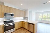 Located at 37 Orange Road in Montclair, NJ, this well-designed 2-bedroom, 2-bathroom residence offers a thoughtful single-level layout with clean, modern finishes throughout. Light wood-tone flooring flows seamlessly across the entire space, complementing a bright, neutral color palette.

The open-concept kitchen is a standout feature, showcasing warm wood cabinetry, a subway tile backsplash, white quartz countertops, and a peninsula with sink overlooking the living area. Stainless steel appliances — including a gas range, microwave, refrigerator, and dishwasher — complete this functional and stylish kitchen.

The primary bedroom is a comfortable retreat with a dedicated closet featuring dual hanging rods for ample storage. Both bedrooms benefit from large windows that frame lush, tree-lined views of the surrounding Montclair landscape, filling the rooms with abundant natural light. The bathrooms are finished with modern wood vanities, white quartz counters, large mirrors, and glass-enclosed showers with clean tile surround.

Additional highlights include two closets for storage, a dedicated laundry room with a stacked GE washer and dryer, and recessed lighting throughout. The overall ambiance is fresh, bright, and move-in ready, reflecting a contemporary aesthetic well-suited for modern living.