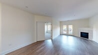 This single-floor residence offers a functional and modern layout across two bedrooms, three bathrooms, and a generous open-concept living area. The kitchen is a standout feature, showcasing rich dark-espresso cabinetry, granite countertops, stainless steel appliances including a French door refrigerator, electric range, and built-in microwave. A large kitchen island with a double undermount sink serves as a central hub, illuminated by stylish pendant lighting. The kitchen flows seamlessly into the living room, which features wood-look flooring, a white-framed fireplace, and a set of French doors that invite natural light and outdoor views. Both bedrooms are carpeted and include ceiling fans with lighting, providing a comfortable and quiet retreat. The primary bedroom is generously sized with ample space. The three bathrooms are finished with tile flooring, dark granite vanity tops, white cabinetry, and brushed nickel hardware; one includes a full soaking tub and shower combination. Additional spaces include two closets and a utility room. Neutral wall tones and consistent modern finishes create a clean, cohesive aesthetic throughout the entire residence.