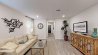 This single-floor residence offers a thoughtfully designed open layout finished with light wood-style flooring and crisp white walls throughout, creating a cohesive and airy atmosphere. The living room is generously proportioned, featuring recessed lighting, a large window with natural light, and a clear sightline down a central hallway connecting the home's key spaces. A dedicated dining area accommodates a full-sized table and sits adjacent to a sliding door, allowing additional natural light to fill the room. The kitchen is well-equipped with dark espresso cabinetry, granite countertops, stainless steel appliances including a side-by-side refrigerator, electric range, and built-in microwave, along with a kitchen island for added workspace. The primary bedroom is spacious with a large window, recessed lighting, and direct access to additional rooms. A secondary bedroom maintains a similarly bright and comfortable character. The bathroom features dark wood vanity cabinetry, granite countertops, a large mirror, and a walk-in shower. Consistent flooring, neutral tones, and a coastal-inspired décor scheme unify the space with a clean, modern sensibility throughout.