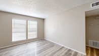 This thoughtfully laid-out one-bedroom, one-bathroom residence spans a single floor and offers a practical, efficient use of space across its living room, bedroom, kitchen, bathroom, closet, and hallway. Light wood-style flooring runs consistently throughout, lending a cohesive and clean aesthetic to each room.

The living area is bright and open, benefiting from a large window fitted with white blinds that allows natural light to fill the room. A notable built-in shelving wall adds both character and functional storage, seamlessly integrated between the living and bedroom areas.

The bedroom is comfortably sized and connects directly to a dedicated walk-in closet outfitted with multi-level shelving and hanging rods on both sides, providing ample organized storage. Textured popcorn ceilings are present throughout, a consistent architectural detail across the unit.

The kitchen features gray cabinetry, speckled quartz-style countertops, and an electric range, offering a clean and functional cooking space. The bathroom is efficiently designed with a full tub-shower combination with white tile surround, a vanity with a matching quartz-style countertop, and brushed nickel fixtures and accessories. The overall ambiance of the unit is neutral and move-in ready, with a clean, understated palette throughout.
