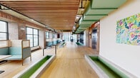 Located at 915 Lafayette Blvd in Bridgeport, Connecticut, this expansive single-floor commercial space delivers a compelling blend of industrial heritage and contemporary design. Throughout, wide-plank light oak hardwood flooring anchors the interior, while striking slatted wood ceilings add warmth and acoustic texture above exposed structural elements and industrial-style ductwork.

The open main area is bathed in natural light through floor-to-ceiling black-framed windows that frame panoramic views of the surrounding harbor and cityscape. Raised concrete planters and partition elements define zones within the expansive floor plate without enclosing them, preserving a sense of openness and flow. Curated nautical-themed artwork punctuates the walls throughout.

A dedicated dining area features teal upholstered booth seating set against original exposed brick walls, creating an inviting, lounge-like atmosphere ideal for collaboration or casual gatherings. A glass-walled conference room with a large boardroom table, mounted display screen, and slatted wood ceiling provides a refined setting for formal meetings.

The well-appointed kitchen includes light wood cabinetry, grey countertops, white subway tile backsplash, stainless steel appliances, and tiled flooring — functional and cleanly designed. Additional open areas throughout the floor offer flexible space suited to a variety of uses, making this a highly versatile and visually distinctive commercial offering.