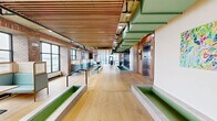 Located at 915 Lafayette Blvd in Bridgeport, Connecticut, this expansive single-floor commercial space delivers a compelling blend of industrial heritage and contemporary design. Throughout, wide-plank light oak hardwood flooring anchors the interior, while striking slatted wood ceilings add warmth and acoustic texture above exposed structural elements and industrial-style ductwork.

The open main area is bathed in natural light through floor-to-ceiling black-framed windows that frame panoramic views of the surrounding harbor and cityscape. Raised concrete planters and partition elements define zones within the expansive floor plate without enclosing them, preserving a sense of openness and flow. Curated nautical-themed artwork punctuates the walls throughout.

A dedicated dining area features teal upholstered booth seating set against original exposed brick walls, creating an inviting, lounge-like atmosphere ideal for collaboration or casual gatherings. A glass-walled conference room with a large boardroom table, mounted display screen, and slatted wood ceiling provides a refined setting for formal meetings.

The well-appointed kitchen includes light wood cabinetry, grey countertops, white subway tile backsplash, stainless steel appliances, and tiled flooring — functional and cleanly designed. Additional open areas throughout the floor offer flexible space suited to a variety of uses, making this a highly versatile and visually distinctive commercial offering.