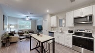 Located at 1720 Crestdale Dr in Houston, Texas, this thoughtfully designed one-bedroom, one-bathroom residence offers a comfortable and modern living experience across a single floor. The open-concept layout flows naturally between the key living spaces, all unified by warm wood-style flooring and a neutral color palette.

The kitchen is a standout feature, showcasing crisp white shaker cabinetry extending to the ceiling for generous storage, light quartz countertops, and a full suite of stainless steel appliances including a refrigerator, electric range, microwave, and dishwasher. A kitchen island with seating provides additional prep and dining space.

The living room is bright and welcoming, featuring a large window that draws in natural light and frames views of the surrounding greenery. A ceiling fan adds to the comfort of the space, which easily accommodates multiple seating arrangements.

The spacious primary bedroom continues the wood-style flooring and includes a ceiling fan, large window with outdoor views, and a dedicated closet for storage. The full bathroom features marble-style tile flooring and wall surround, with a tub-shower combination and built-in closet space for added functionality. Clean, modern finishes throughout give this residence a polished and move-in-ready feel.