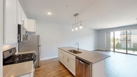 This well-appointed one-bedroom, one-bathroom residence at Watermark Terrace in Elgin, Illinois offers a thoughtfully designed layout with modern finishes throughout. The open-concept kitchen and living area serves as the heart of the home, featuring warm wood-look vinyl plank flooring, crisp white shaker cabinetry, a subway tile backsplash, and a large central island with a quartz countertop, undermount sink, and pendant lighting. Stainless steel appliances, including a gas range, built-in microwave, refrigerator, and dishwasher, complete the kitchen. The adjacent living area is bright and airy, with sliding glass doors that open onto a private balcony overlooking the community grounds. The spacious bedroom is carpeted for comfort and benefits from large windows that bring in generous natural light and neighborhood views. It connects to the full bathroom, which features warm wood-look flooring, a wide white vanity with ample storage, a large mirror, and a tiled walk-in shower with sliding glass doors. Two closets — including a walk-in closet with wire shelving systems — provide excellent storage. Neutral tones and clean architectural lines give the entire residence a contemporary, move-in-ready feel.