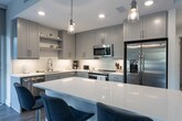 Located in the heart of Midtown Atlanta, this contemporary single-floor residence at 902 W Peachtree St NW offers a thoughtfully designed layout with modern finishes throughout. The open-concept living area is anchored by dramatic floor-to-ceiling windows that flood the space with natural light and frame sweeping views of the Atlanta skyline and surrounding greenery. Wood-look flooring runs throughout, providing a warm contrast to the clean, neutral color palette.

The kitchen is a standout feature, equipped with gray shaker-style cabinetry, white quartz countertops, stainless steel appliances, a built-in wine cooler, and a large center island ideal for both meal prep and casual dining. Pendant lighting and additional window views complete this well-appointed culinary space.

The bedrooms are generously sized, each styled with comfort in mind and featuring large windows that bring in ample daylight. The primary bedroom benefits from direct city views through expansive glazing and is complemented by a well-organized walk-in closet with built-in shelving and drawers. The en-suite bathroom includes a stylish double vanity with gray cabinetry, tile flooring, and polished fixtures. A second full bathroom with a soaking tub and additional closet access provides convenience for guests.