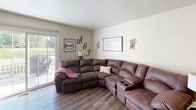 Located on Highbrook Court in Hudsonville, Michigan, this three-floor home offers a thoughtfully organized layout across its levels. The main floor features a welcoming living room with wood-look flooring, neutral walls, and a sliding glass door that opens to the outdoors, filling the space with natural light. The kitchen is well-equipped with white cabinetry, stainless steel appliances including a refrigerator, electric range, and built-in microwave, complemented by durable countertops and a double sink. An adjacent entry area connects seamlessly to the main living spaces. Two full bathrooms are present in the home — one featuring a vanity with white cabinetry and wood-look flooring, and another with a matching vanity and tub/shower combination. The upper level hosts multiple bedrooms, each with plush carpeting and natural light from windows with blinds. The bedrooms offer generous closet space and a clean, comfortable atmosphere. The lower level provides additional living space with carpeted flooring, neutral tones, and a cozy sectional layout — ideal for a recreation or media room. A staircase connects all three levels, visible in the dollhouse view, tying together a practical and comfortable home in a quiet Hudsonville neighborhood.