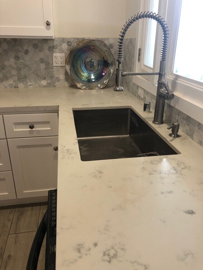 Kitchen has high end quartz counters with black stainless appliances - 4228 Lockwood Ave