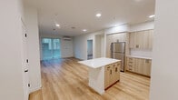 Located at 6021 Lakewood Dr W in University Place, WA, this well-appointed 2-bedroom, 2-bathroom residence offers a thoughtfully designed single-floor layout. The open-concept living, dining, and kitchen area serves as the heart of the home, bathed in natural light from large sliding glass doors and fitted with light oak luxury vinyl plank flooring throughout. The modern kitchen is a standout feature, boasting light wood cabinetry, a white quartz center island, white quartz countertops, stainless steel appliances including a refrigerator, range, microwave, and dishwasher, and open shelving for added functionality. A wall-mounted mini-split system provides efficient climate control in the living area. The primary bedroom offers a generous footprint with sliding glass door access and its own mini-split unit, while the second bedroom features plush carpeting and a bright window with blinds. Both bathrooms are finished in a clean, contemporary style with light wood vanities, white countertops, and matte black hardware accents. One bathroom includes a full soaking tub. The residence also includes a dedicated laundry area and five closets, providing abundant storage throughout.