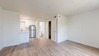 Located at 5333 E Thomas Rd in Phoenix, AZ, this efficiently designed studio unit offers a thoughtfully arranged single-floor layout. Light-toned hardwood-style flooring runs consistently throughout the space, creating a cohesive and clean aesthetic from entry to back wall.

The combined kitchen and living area forms the heart of the unit. The kitchen is outfitted with crisp white shaker-style cabinetry, a marble-look countertop with a peninsula overhang ideal for casual seating, a stainless steel refrigerator, and a stainless steel sink. A recessed panel ceiling light brightens the kitchen area. The open layout allows the living space to flow naturally from the kitchen, with a large window fitted with vertical blinds that invites natural light into the room.

The bathroom is clean and functional, featuring a full-size soaking tub with shower combination, a white vanity with storage, and wood-look flooring consistent with the rest of the unit. A dedicated closet provides practical storage separate from the main living area.

The unit's white walls and neutral palette contribute to a bright, airy feel throughout. The layout is compact yet well-organized, making efficient use of every square foot. Ceiling-mounted HVAC vents ensure climate comfort — a valuable feature in the Phoenix, AZ environment.
