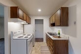 Located at 2345 North Harrison Road in East Lansing, Michigan, this one-bedroom, one-bathroom unit offers a practical and efficient single-floor layout. The galley-style kitchen is well-appointed with warm wood cabinetry on both sides, white countertops, a double-basin sink, and white appliances including a coil-top range and refrigerator. Tile flooring and under-cabinet range ventilation complete the functional kitchen design. The layout opens toward a combined living and dining area, carpeted in neutral tones, with a ceiling fan overhead providing comfort and airflow. The living area features a large window with vertical blinds, a wall-mounted air conditioning unit, and a baseboard heating system, ensuring year-round climate control. The bedroom is a comfortable size, also carpeted, with a window allowing natural light and featuring baseboard heat. Three closets throughout the unit provide ample storage. The bathroom includes a vanity with a light countertop, tile flooring, a toilet, and a bathtub with a shower and curtain rod. A dedicated entrance area completes the layout. The unit's clean white walls and consistent neutral palette create a simple, livable atmosphere throughout.