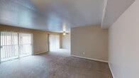 This single-story residence in Houston, TX offers a practical and well-organized layout across one floor. The living area is generously proportioned, featuring neutral beige walls, plush wall-to-wall carpeting, and a textured ceiling. A ceiling fan with a light fixture provides both comfort and illumination, while sliding glass doors fitted with vertical blinds open to the exterior, allowing natural light to fill the space. The entry area transitions seamlessly into the main living zone, which offers ample room for a variety of furniture arrangements.

The galley-style kitchen is efficiently designed, featuring white cabinetry on both sides, dark laminate countertops, wood-look flooring, and white appliances including a refrigerator, electric range, and dishwasher. A double-basin sink is positioned beneath overhead cabinets, maximizing storage and functionality throughout the compact but well-equipped space.

The bedroom is comfortably sized with soft carpeting, a ceiling fan, and two windows fitted with blinds that provide natural light and exterior views. The full bathroom includes a wide vanity with dark countertops, white cabinetry, a large mirror with overhead lighting, wood-look flooring, and a full tub-shower combination.