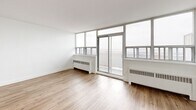 Located on the 9th floor at 2050 Keele Street in Toronto's Mount Dennis neighbourhood, this two-bedroom, one-bathroom unit offers a bright and modern living environment. The open-concept living and dining area is generously proportioned, featuring light hardwood flooring, crisp white walls, and floor-to-ceiling windows that flood the space with natural light and frame sweeping views of the surrounding cityscape. A private balcony is accessible directly from the living area, extending the sense of openness. The kitchen is well-appointed with white shaker cabinetry, dark stone countertops, a classic subway tile backsplash, stainless steel appliances including a refrigerator, electric range, built-in microwave, and dishwasher, and a central island that provides additional prep and storage space. Both bedrooms are comfortably sized with large windows overlooking the city; the primary bedroom includes a mirrored sliding closet. The bathroom features a full soaker tub finished with clean white subway tile surround. Light hardwood flooring flows consistently throughout the unit, contributing to a cohesive and contemporary aesthetic. Baseboard heating units are present throughout, ensuring year-round comfort in this well-designed urban residence.