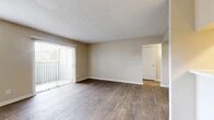 Located at 2121 Madison Dr in Arlington, TX, this one-bedroom, one-bathroom unit offers a thoughtfully organized single-floor layout. The living room is the heart of the space, featuring durable wood-style flooring, neutral beige walls, and a textured ceiling. Natural light pours in through a large sliding glass door fitted with vertical blinds that opens to an outdoor patio, complemented by an additional window that further brightens the room. A half-wall pass-through connects the living area to the kitchen, which includes white cabinetry, light countertops, and a skylight overhead that adds an extra source of natural illumination. The bedroom is carpeted for comfort, offering a welcoming retreat with windows dressed in horizontal blinds. It connects to a generous walk-in closet with built-in shelving rods, providing ample storage. The bathroom is clean and functional, featuring wood-style flooring, a tiled shower-tub combination, and a vanity with a stone-look countertop. A hallway efficiently connects all areas of the unit. Throughout the space, consistent neutral tones and clean finishes create a cohesive, move-in-ready atmosphere.