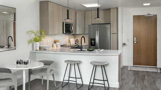 Cocina de apartamento con electrodomésticos de acero inoxidable, encimeras de cuarzo y suelos que imitan la madera. - Griffis Cheesman Park