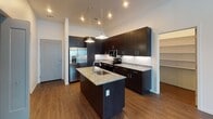 This well-appointed single-floor residence showcases a contemporary design with a cohesive palette of dark espresso cabinetry, granite countertops, and warm wood-look flooring throughout the main living areas. The kitchen serves as a standout feature, centered around a large island with an undermount sink and pendant lighting overhead. Rich dark cabinetry extends to the ceiling, providing ample storage, while stainless steel appliances — including a side-by-side refrigerator with ice maker, electric range, and built-in microwave — complete the modern culinary space. A white subway tile backsplash adds a clean, polished contrast.

The living area is bright and open, benefiting from large windows that invite natural light and offer outdoor views, complemented by a ceiling fan above. Bedrooms feature plush carpeting, ceiling fans, and generous proportions, with one bedroom offering direct access to a full bathroom.

The bathrooms are finished with matching granite vanities and dark cabinetry. The primary bathroom includes a spacious glass-enclosed walk-in shower clad in marble-style tile, while the secondary bathroom offers a marble-tiled tub-shower combination. A walk-in closet with built-in shelving and a dedicated laundry area add everyday convenience to this thoughtfully designed residence.